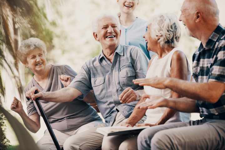 Residents enjoying conversation and laughter at Watermere at Firewheel in Garland, TX, during a sunny afternoon in the senior living community.
