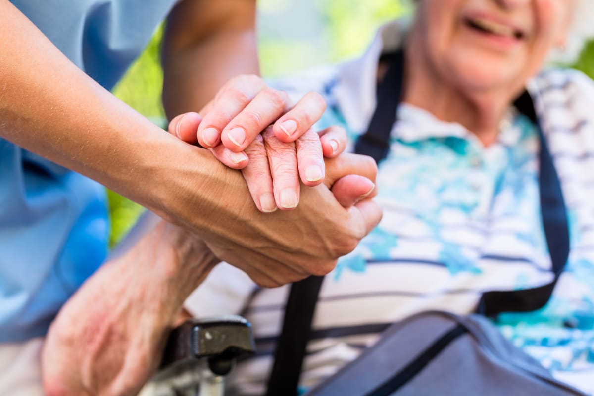 A resident holding hands with a caretaker at Keystone Place at Magnolia Commons in Glen Carbon, Illinois