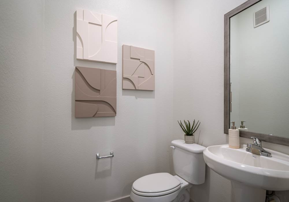 Small apartment powder room featuring a white pedestal sink with chrome faucet at Charleston at Fannin Station in Houston, Texas