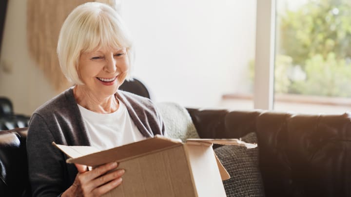 Happy elderly woman holding a box