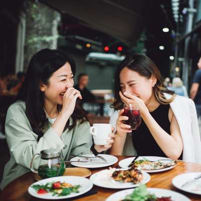 Two women sharing a laugh while having a meal near Station 3700 in Euless, Texas