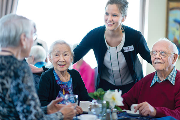 Dining staff visiting with resident at Wyndham Court of Plano in Plano, Texas