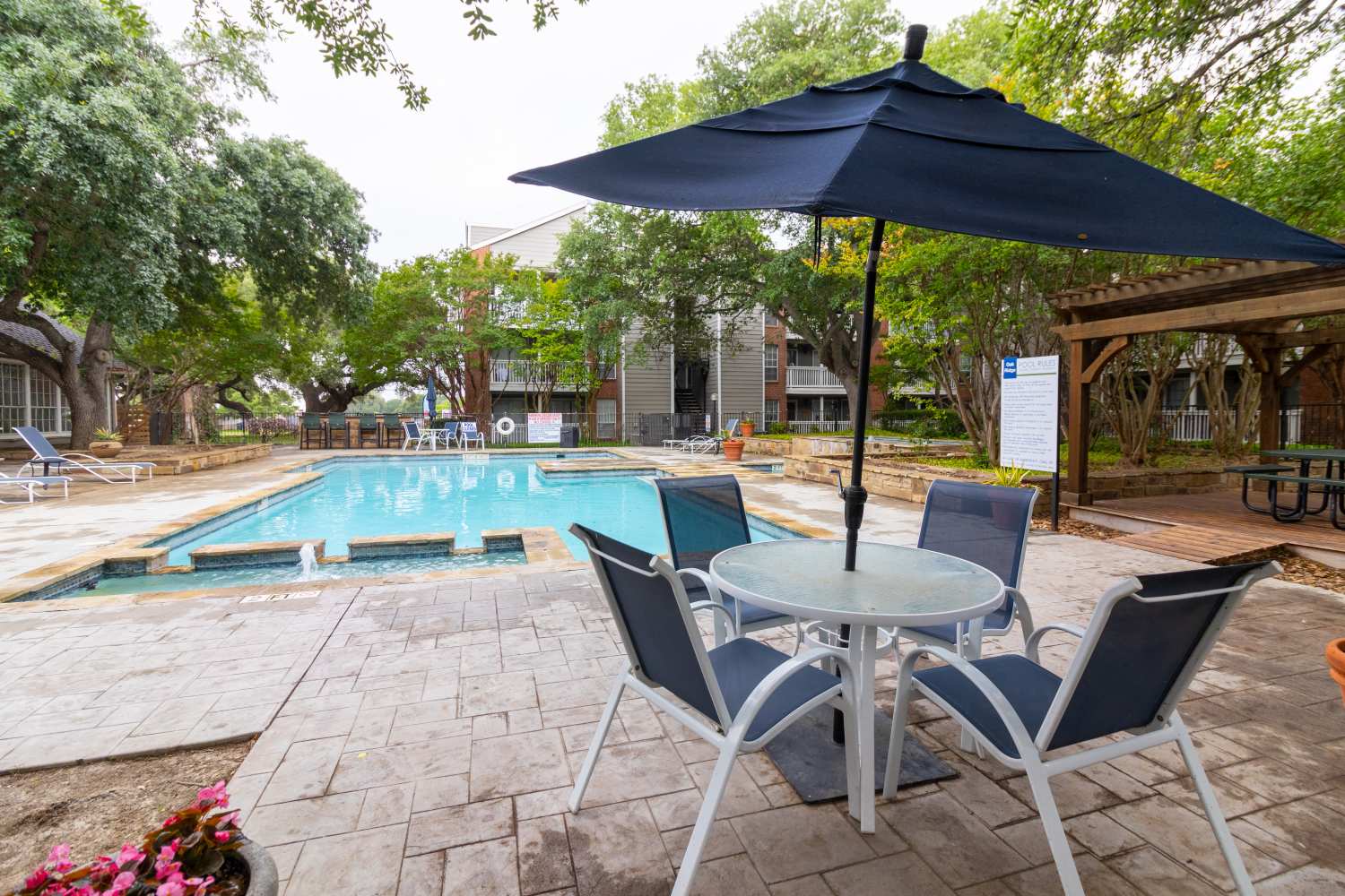 Swimming pool with canopy and lounge seating at Oak Ridge Apartments in San Antonio, Texas