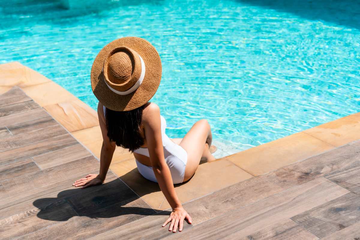 Woman putting her feet in the pool and looking at her phone at Uptown La Grange in La Grange, Illinois