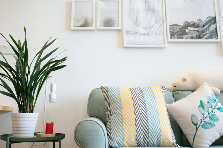 a clean and organized sofa with comfy throw pillows and a side table with a plant on it