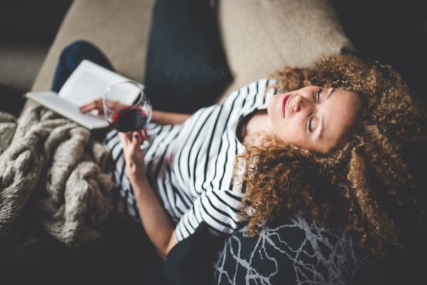 A woman reading a book and drinking wine at Lakeside Apartments in Wheaton, Illinois