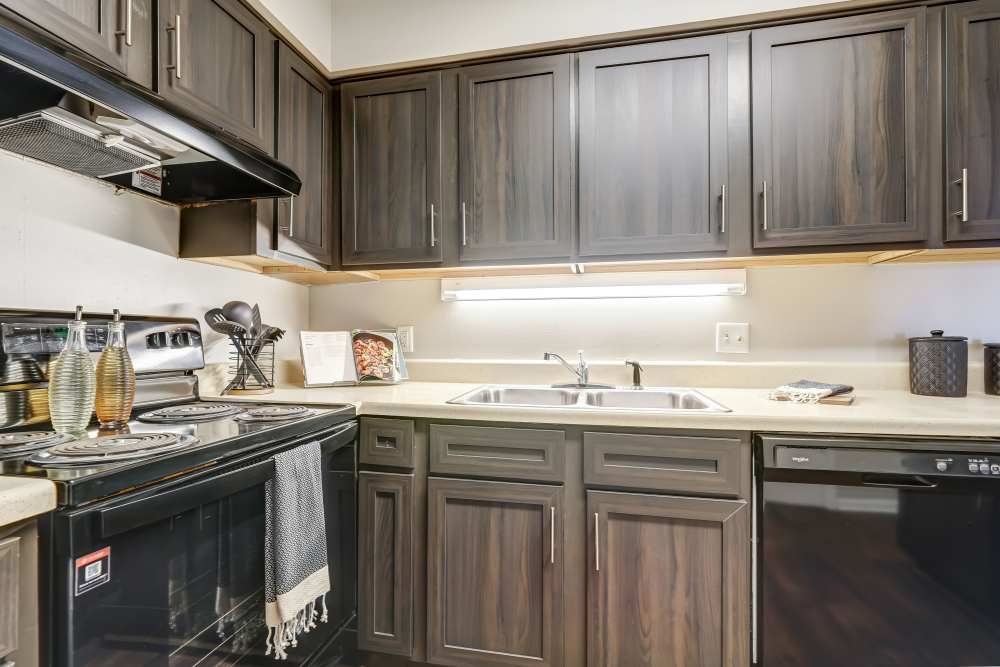 Kitchen with espresso cabinets and black appliances at River Park Tower Apartment Homes in Newport News, Virginia