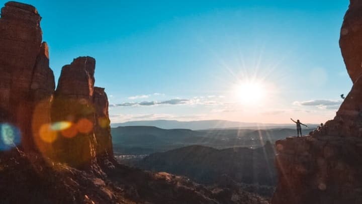 Arizona rock formations overlooking valley with hiker in the distance