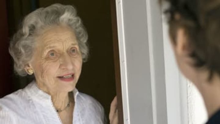An elderly woman answering the front door at {{location_name}} in {{location_city}}, {{location_state_name}}