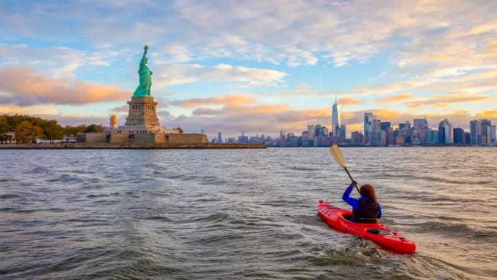 Woman kayaking Hudson River toward the Statue of Liberty