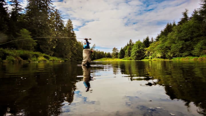 man standing in river casting a fly fishing reel