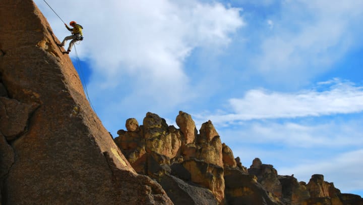 rock climber descending rock face in desert landscape