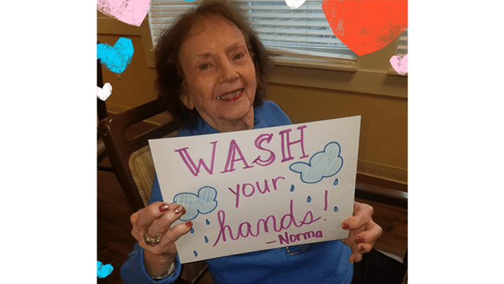 Morningside Place resident holding "wash your hands" sign