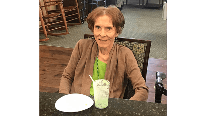 Willowbrook Place resident sitting at a table with a drink