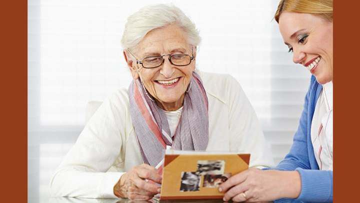 Senior woman with dementia with her daughter viewing photo album