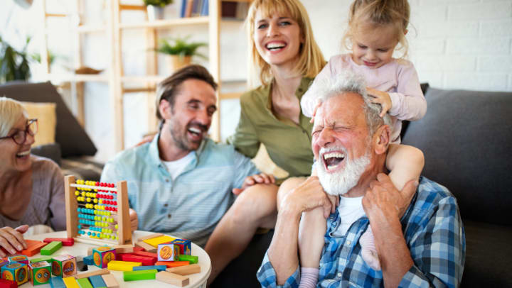 an adult laughing with his granddaughter and family