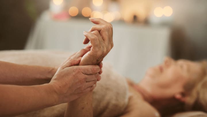 a senior lady receiving massage therapy on her hands