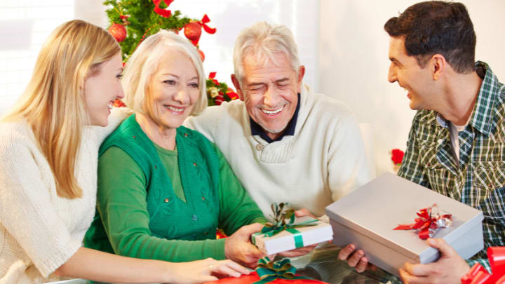 an elderly couple with their children sharing Christmas presents
