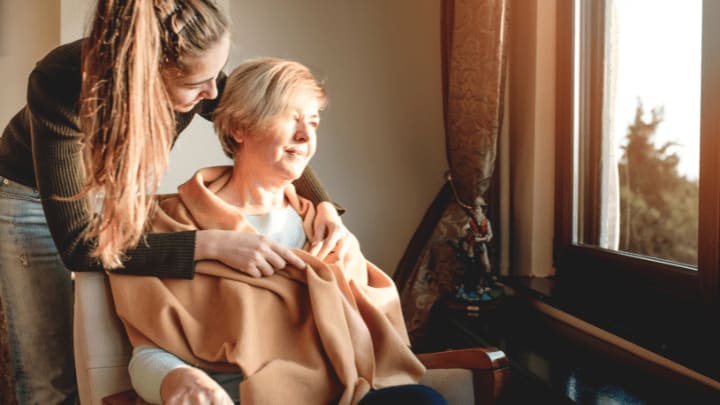 a caregiver with an elderly woman hugging each other