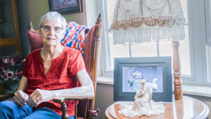 Alvada sits in her chair next to a photo of her grandkid