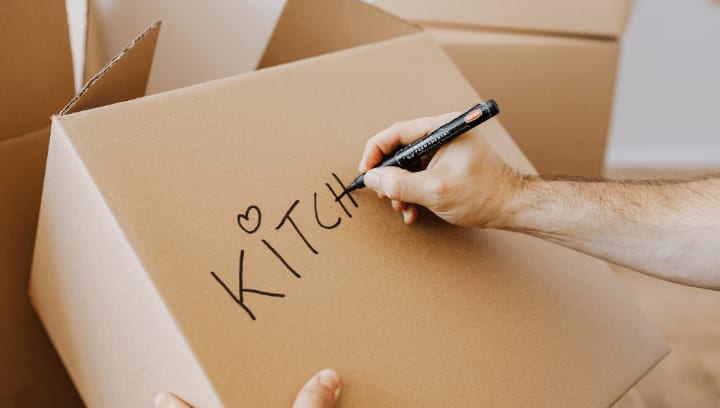 A hand labelling a box "kitchen" before it is stored in Portland, Oregon