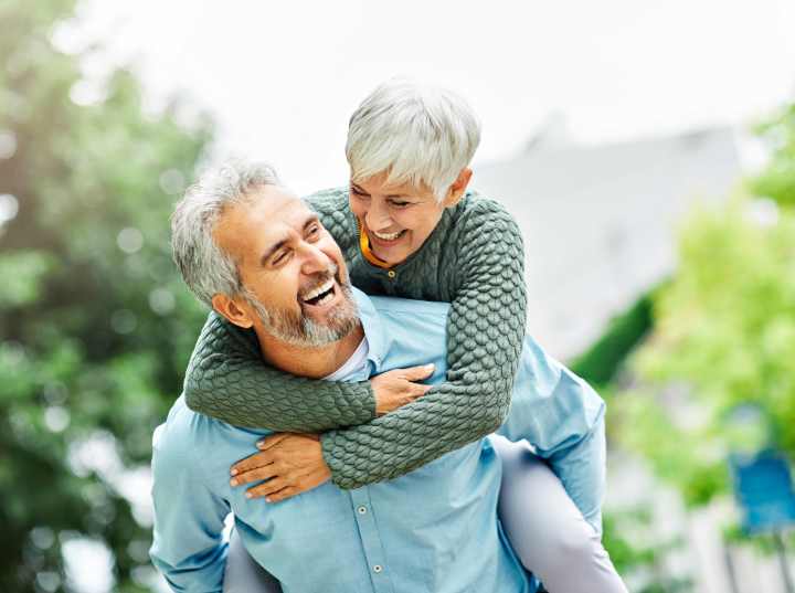Happy senior couple smiling together outdoors, enjoying quality time and a joyful lifestyle.