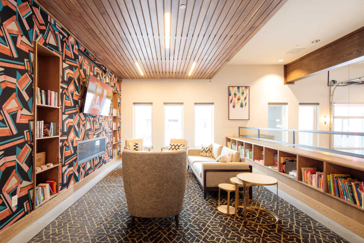 Cozy community lounge with stylish decor, comfortable seating, and bookshelves filled with colorful books at Viña Apartments in Denver, Colorado 