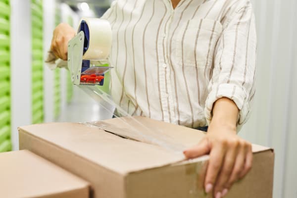 Woman sealing a box with packing tape at A Storage Place