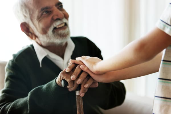 A resident with a cane assisted by a staff member of AgeWell Living