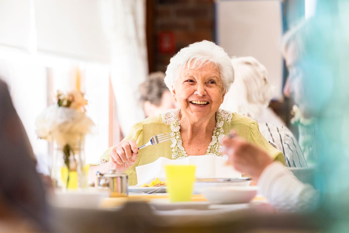 Resident smiling at the breakfast table at Worthington Manor in Conroe, Texas