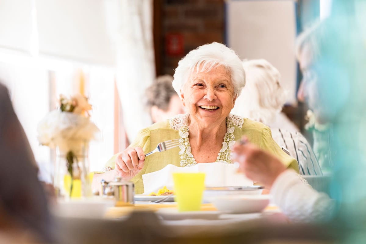 Resident smiling at the breakfast table at Crescent Senior Living in Sandy, Utah