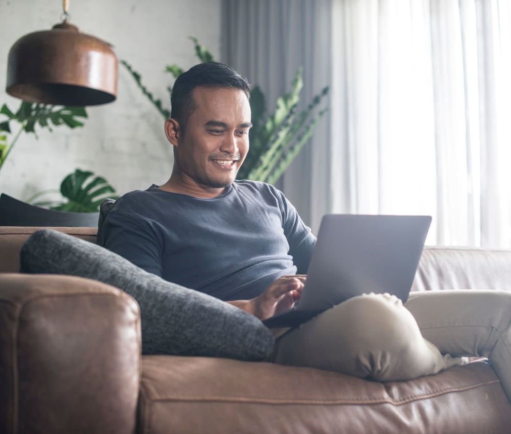 Resident working on a laptop from the couch of his new apartment at Tower 801 in Seattle, Washington