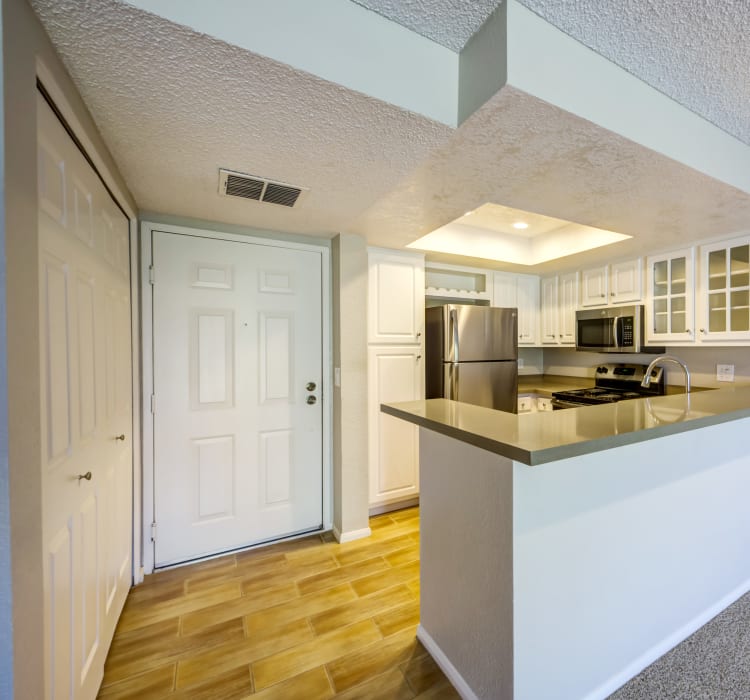 Model home's entryway and kitchen with hardwood flooring at Sofi Irvine in Irvine, California