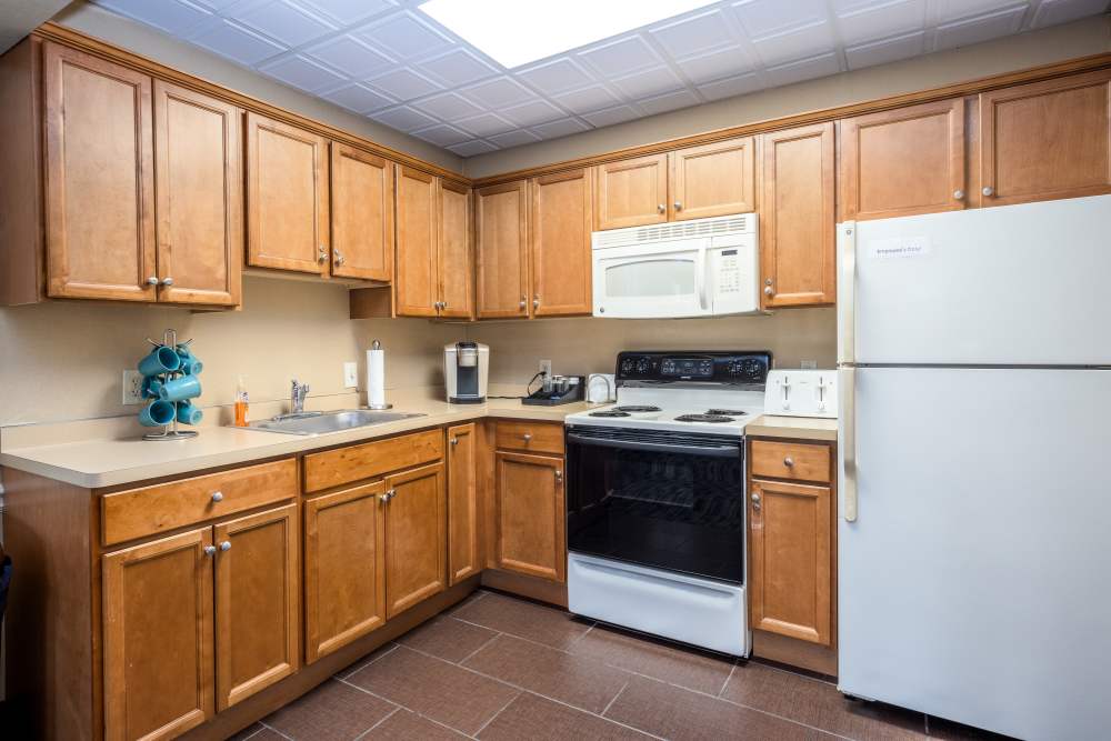 Kitchen with wooden cabinets, refrigerator at Greece Commons Apartments in Rochester, New York