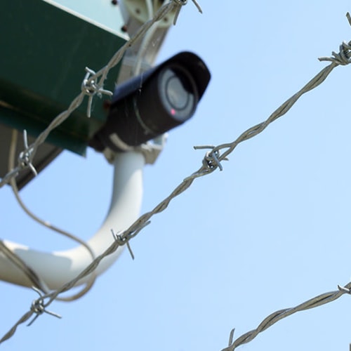 Security camera behind barbed wire fence at Red Dot Storage in Searcy, Arkansas