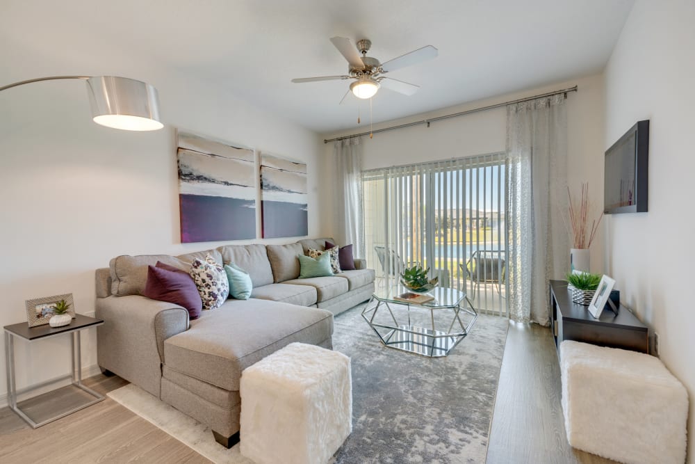 Model living room with hardwood style flooring and ceiling fan at Champions Vue Apartments in Davenport, Florida