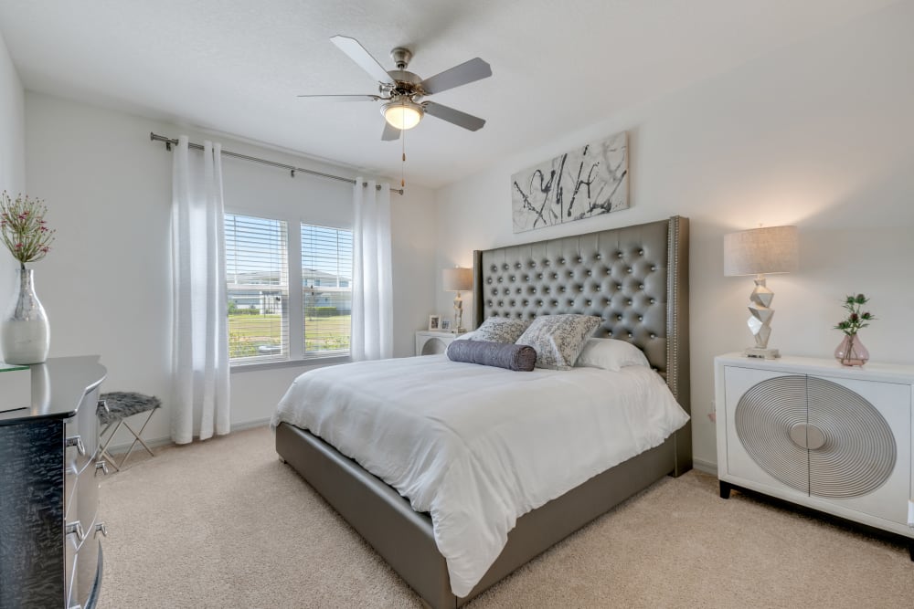 Master bedroom with ceiling fan and plush carpeting at Champions Vue Apartments in Davenport, Florida