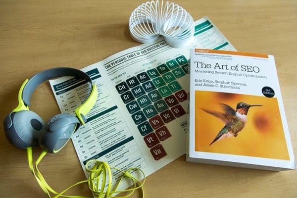 Neon yellow and grey headphones, white slinky, printed marketing collateral with graphic of a periodic table, and a book titled