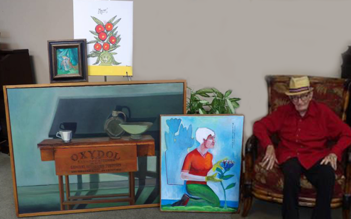 Gary Adamson is seated among displays of his paintings around him