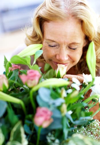 A resident smelling flowers near The Claiborne at Hattiesburg Independent Living in Hattiesburg, Mississippi. 