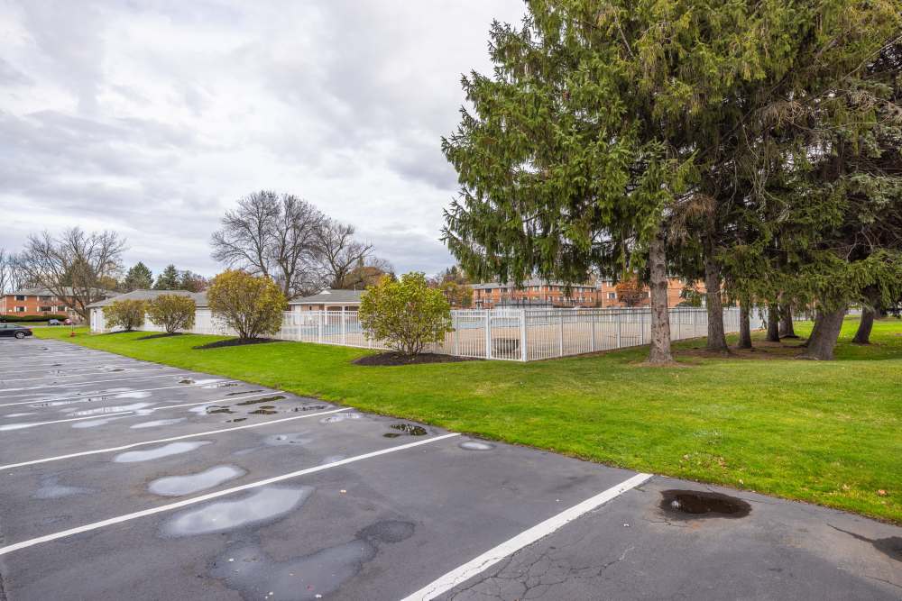 A view of parking lot next to a grassy area at Greece Commons Apartments in Rochester, New York