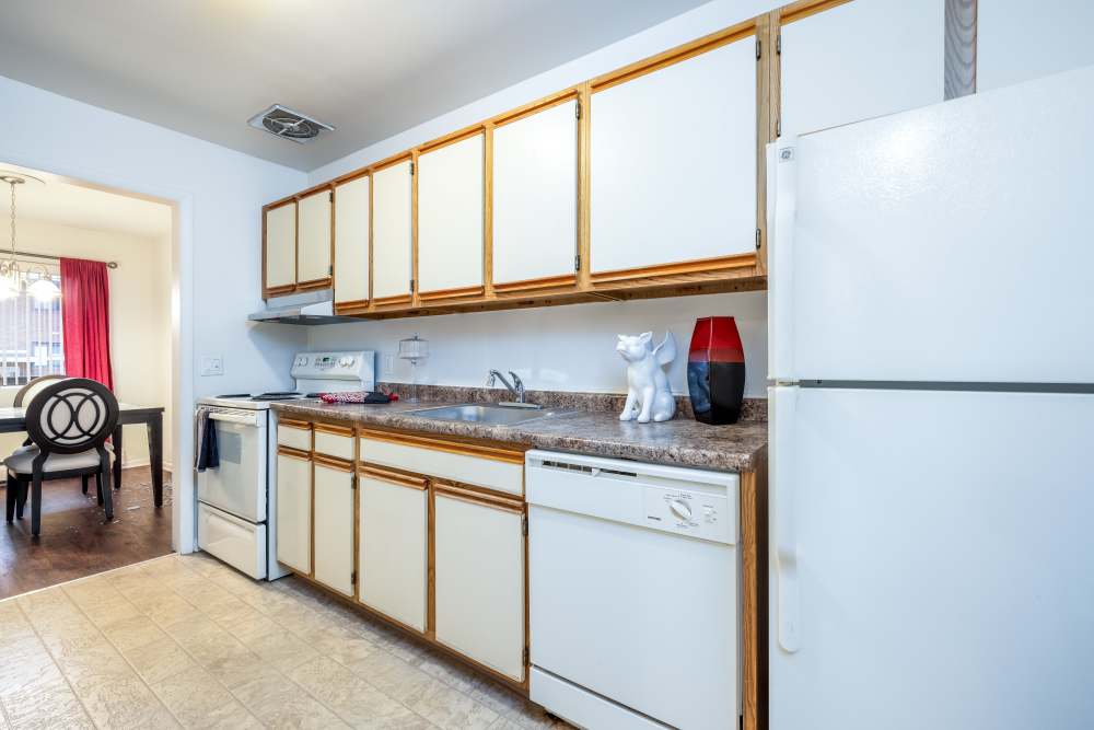 Kitchen with a sink, wooden cabinets and a refrigerator at Greece Commons Apartments in Rochester, New York