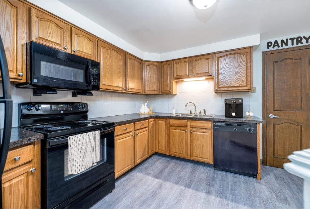 Kitchen with oak cabinets and black appliances at Green Lake Apartments & Townhomes in Orchard Park, New York