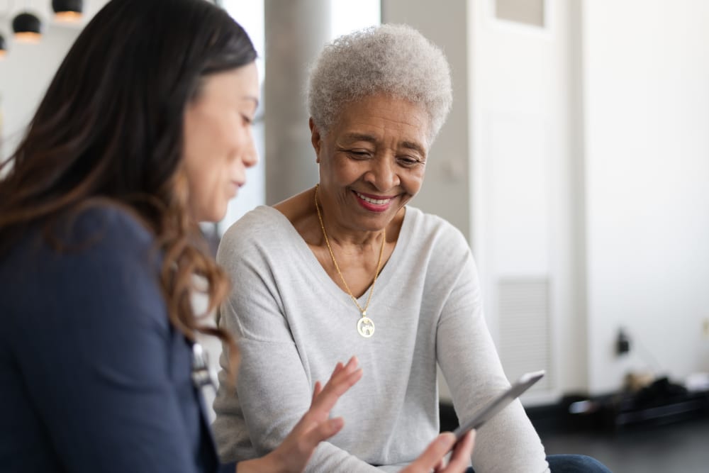 A resident and a lady looking at a mobile phone at Sunshine Villa, A Merrill Gardens Community in Santa Cruz, California. 