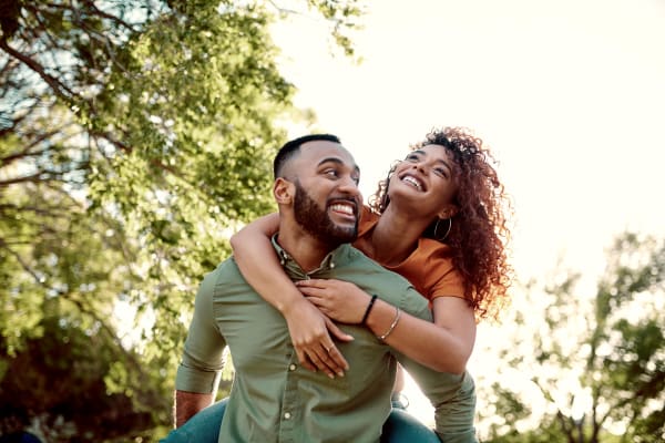 A smiling woman being carried on a mans back outside near EOS in Orlando, Florida