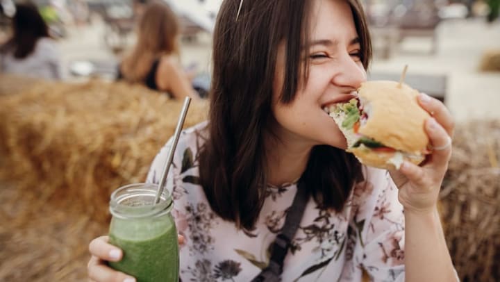 person holding a smoothie and eating a sandwich | easy sack lunch ideas