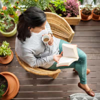 A woman reading on her balcony at Retreat at the Park in Burlington, North Carolina