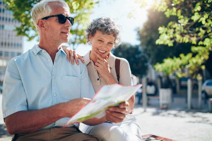 Two happy seniors reviewing papers together outdoors, enjoying their time in a 55+ community.