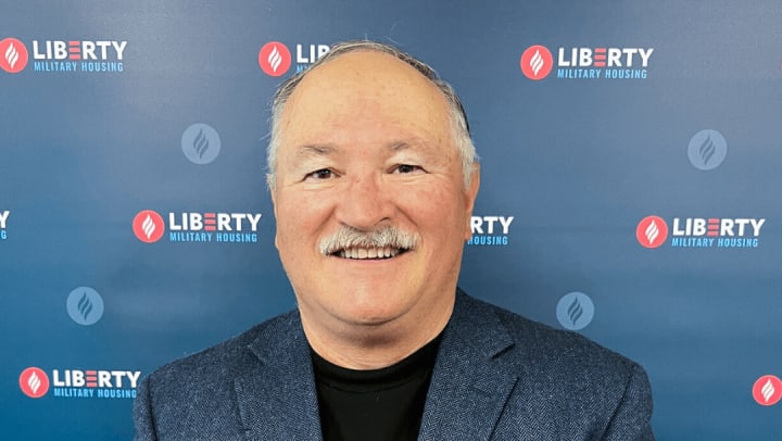Jorge Parada pictured smiling Infront of Liberty Military Housing logo photo backdrop 
