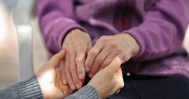 a senior lady and her daughter holding hands